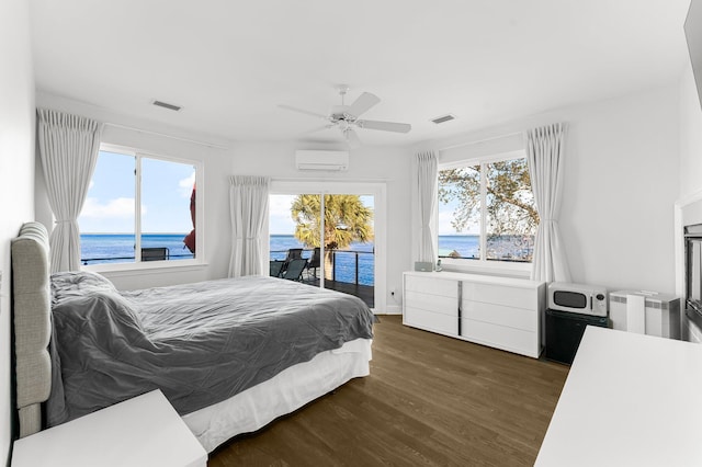 bedroom with dark hardwood / wood-style flooring, ceiling fan, a water view, and multiple windows