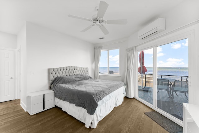 bedroom with a wall mounted air conditioner, access to outside, a water view, ceiling fan, and dark hardwood / wood-style floors