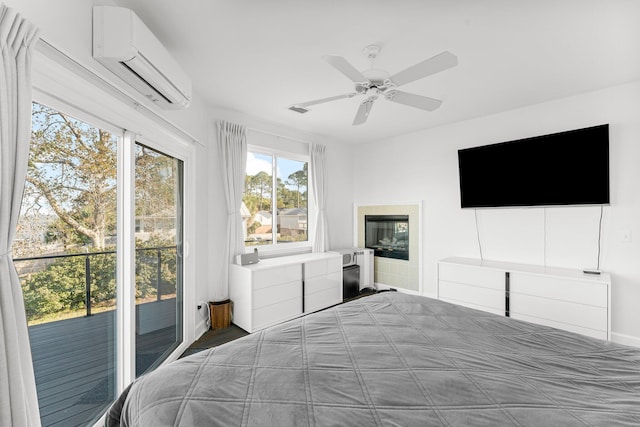 bedroom featuring a wall mounted air conditioner, ceiling fan, access to exterior, and a fireplace