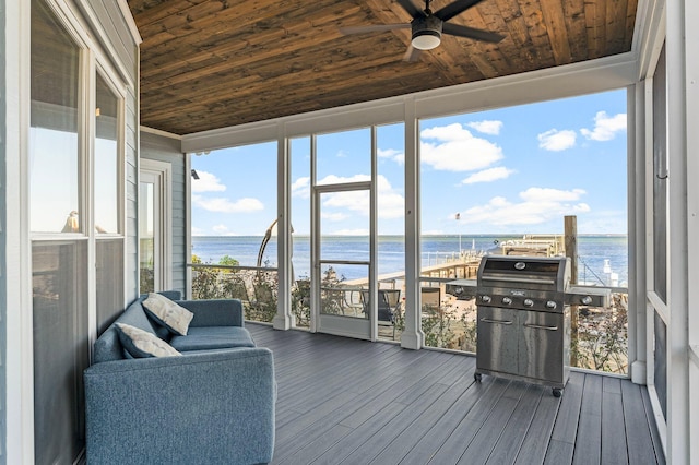 sunroom with ceiling fan, a water view, and wood ceiling