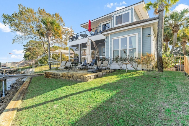 rear view of house featuring a balcony, a patio area, and a lawn