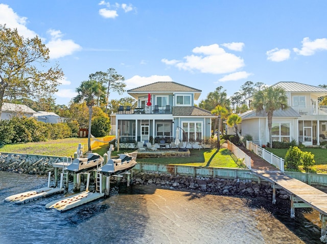 back of house featuring a yard, a sunroom, a balcony, and a water view