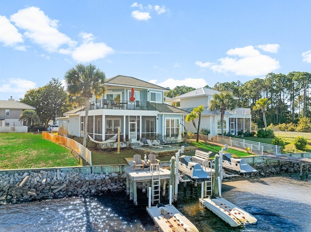 back of house with a sunroom, a water view, a balcony, and a lawn