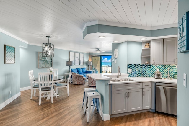 kitchen featuring a breakfast bar, sink, stainless steel dishwasher, gray cabinets, and dark hardwood / wood-style flooring