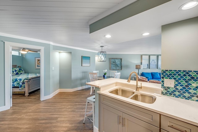 kitchen featuring sink, crown molding, light hardwood / wood-style flooring, decorative light fixtures, and a kitchen bar