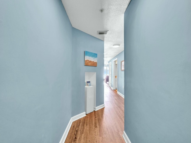 hallway featuring wood-type flooring and a textured ceiling