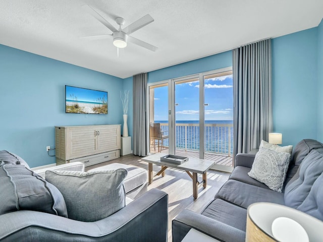 living room with ceiling fan, light hardwood / wood-style flooring, and a textured ceiling