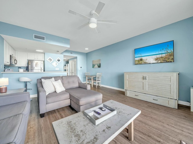 living room featuring ceiling fan and light hardwood / wood-style flooring