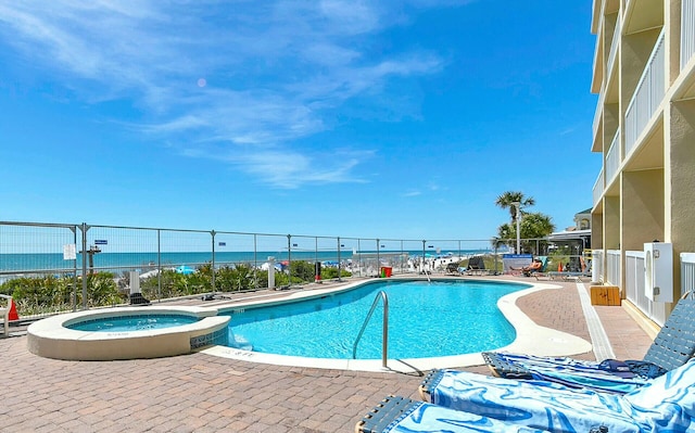 view of pool featuring a water view, a community hot tub, and a patio