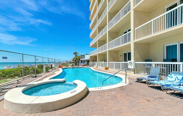 view of swimming pool with a water view and a hot tub