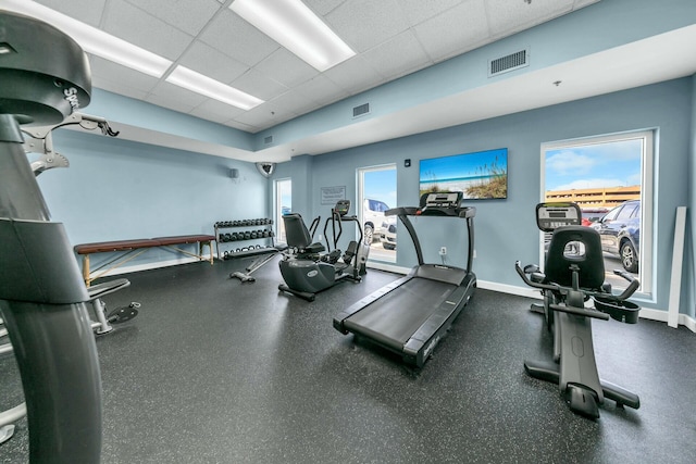 workout area featuring a paneled ceiling and a healthy amount of sunlight