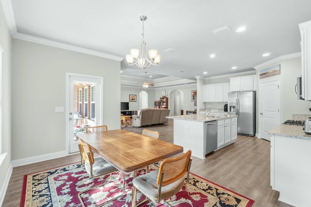 dining room with sink, light hardwood / wood-style flooring, an inviting chandelier, and ornamental molding