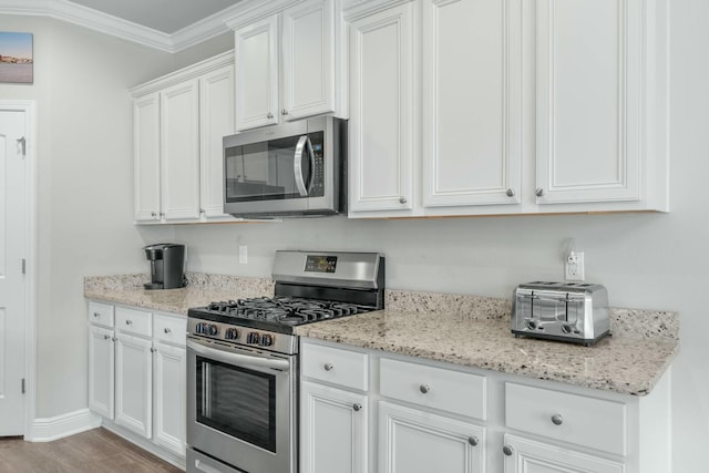 kitchen featuring appliances with stainless steel finishes, light stone counters, crown molding, white cabinets, and light hardwood / wood-style floors