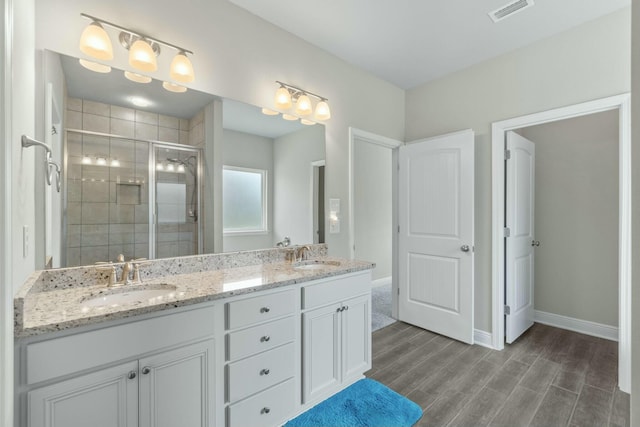 bathroom with wood-type flooring, vanity, and a shower with door