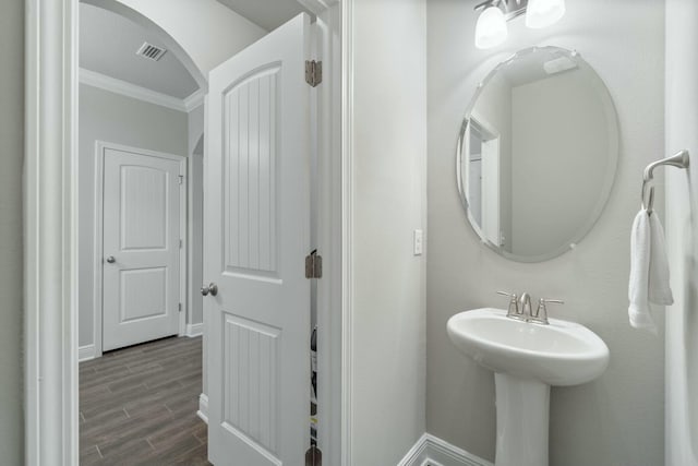 bathroom with hardwood / wood-style floors, ornamental molding, and sink