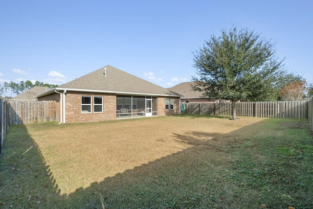 back of property with a lawn and a sunroom