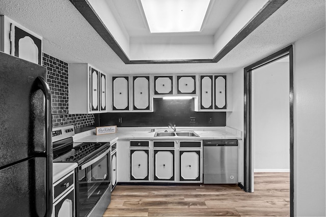 kitchen featuring a raised ceiling, sink, decorative backsplash, wood-type flooring, and stainless steel appliances