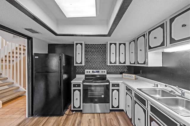 kitchen with light wood-type flooring, black fridge, a textured ceiling, sink, and stainless steel electric range