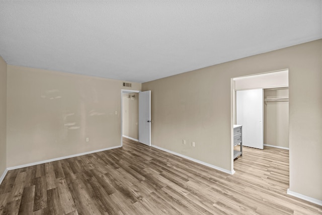 unfurnished bedroom with a closet, light hardwood / wood-style floors, and a textured ceiling