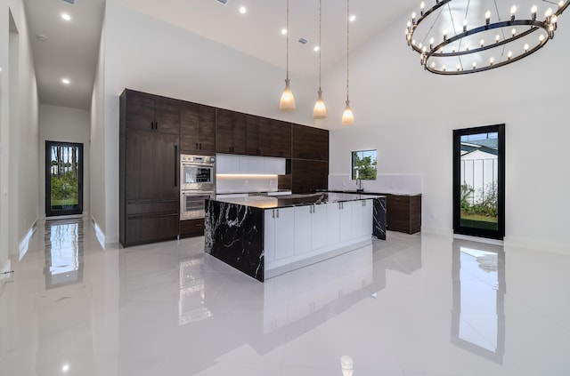 kitchen featuring pendant lighting, a center island, a healthy amount of sunlight, and a high ceiling