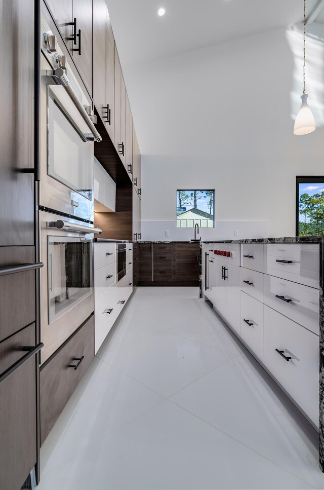 kitchen with light tile patterned floors, white cabinets, stainless steel appliances, and decorative light fixtures