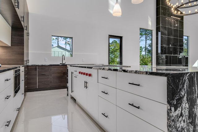 kitchen featuring pendant lighting, white cabinetry, a healthy amount of sunlight, and black oven