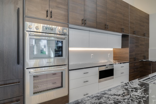 kitchen featuring stone countertops, refrigerator, backsplash, and double oven