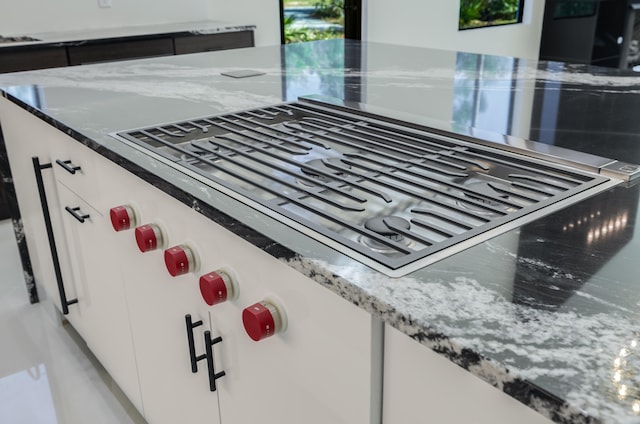 details featuring light stone countertops, white cabinetry, and stainless steel gas stovetop