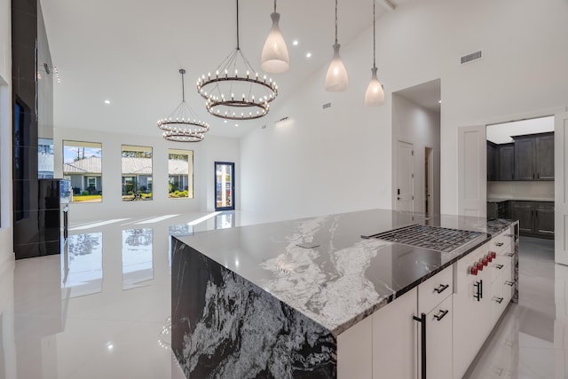 kitchen with white cabinets, a spacious island, dark stone countertops, and high vaulted ceiling