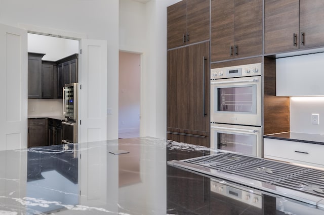 kitchen featuring paneled built in refrigerator, stainless steel double oven, stone countertops, and dark brown cabinetry