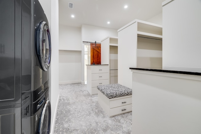 washroom featuring a barn door and stacked washer / drying machine