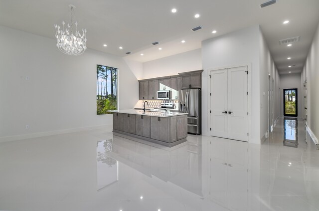 kitchen with stainless steel appliances, an inviting chandelier, backsplash, a spacious island, and dark brown cabinets