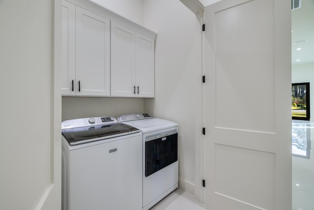 washroom with washing machine and clothes dryer and cabinets