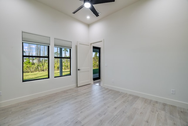 unfurnished room featuring a towering ceiling, light hardwood / wood-style flooring, and ceiling fan