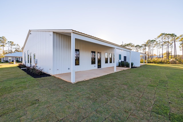 back house at dusk featuring a patio area and a yard