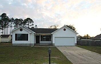 ranch-style home with a front yard, driveway, and an attached garage