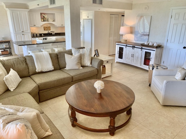 tiled living room with crown molding and sink