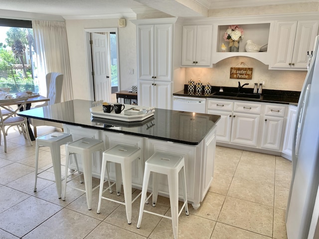 kitchen featuring white cabinetry, a center island, white appliances, and sink