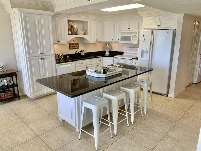 kitchen featuring a center island, white cabinets, and white appliances