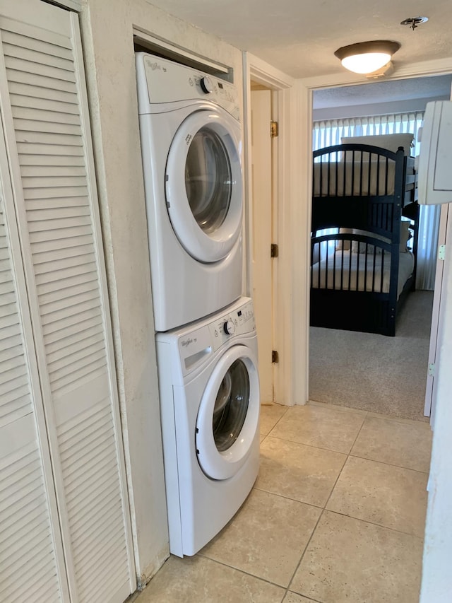 laundry area featuring light carpet and stacked washer / dryer