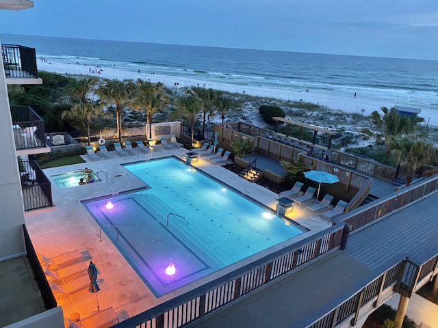 view of pool featuring a beach view, a patio, and a water view