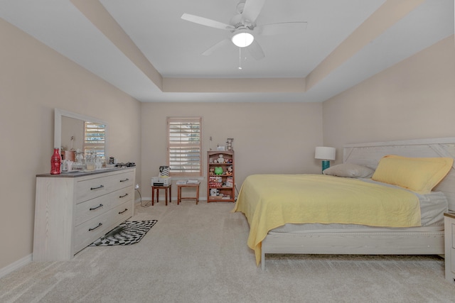 carpeted bedroom with a tray ceiling and ceiling fan