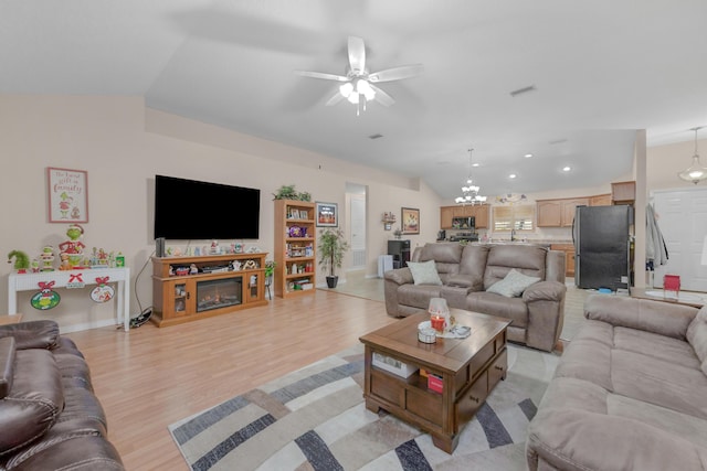 living room with lofted ceiling, light wood-type flooring, and ceiling fan with notable chandelier