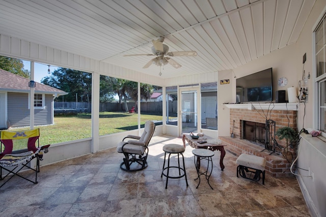 sunroom with ceiling fan, a fireplace, and wooden ceiling