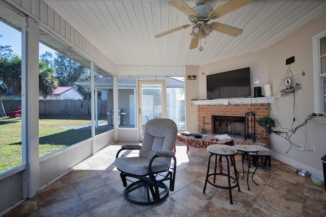 sunroom / solarium with a brick fireplace, ceiling fan, and wooden ceiling