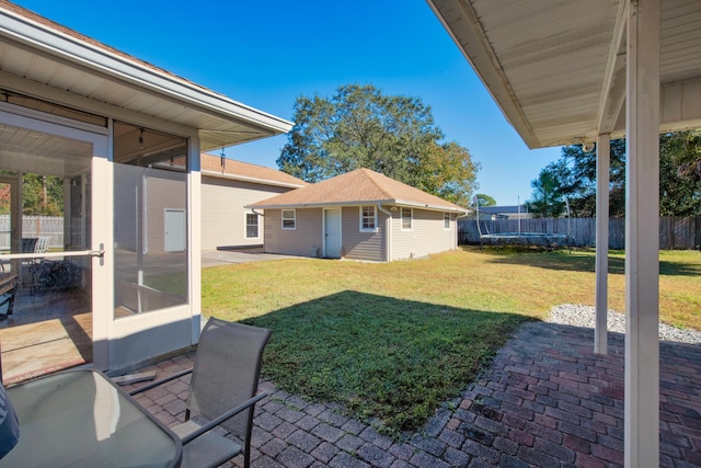 view of yard with a sunroom, an outbuilding, and a patio