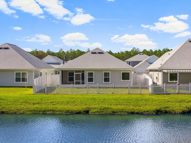 back of property featuring a water view and a lawn