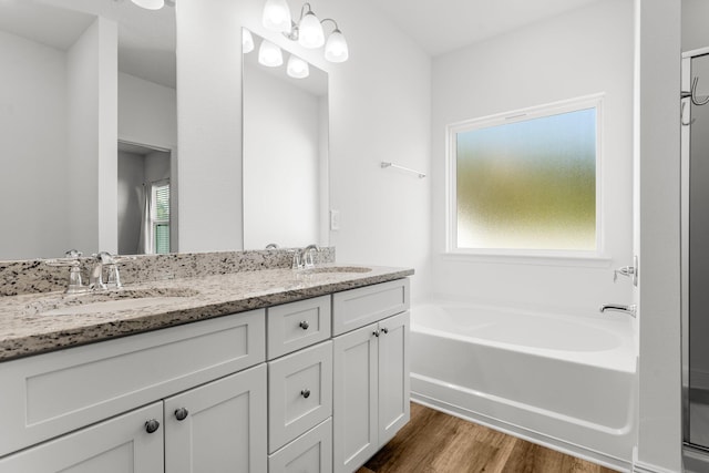 bathroom featuring hardwood / wood-style flooring, vanity, and a tub