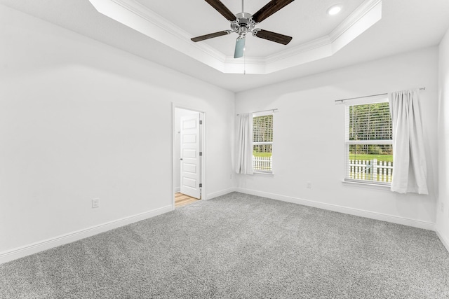 carpeted empty room featuring plenty of natural light, ceiling fan, a raised ceiling, and crown molding