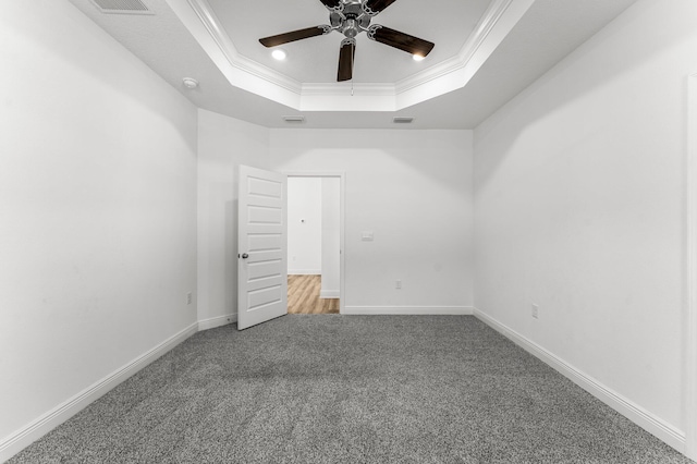 carpeted spare room with a tray ceiling, ceiling fan, and ornamental molding